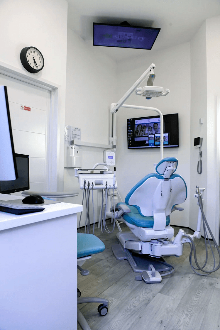 A treatment room at Campos Dental Edgware — modern dental chair under a ceiling-mounted light, with a wall-mounted monitor and a clean, hygienic fit-out.