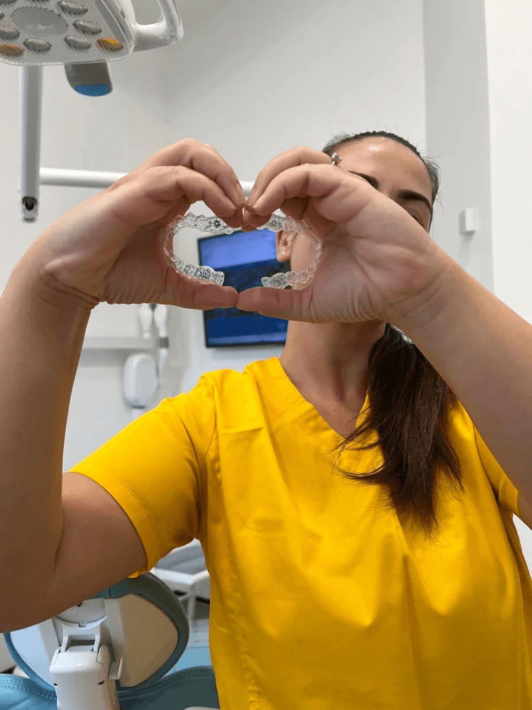 A clinician at Campos Dental Edgware holding a clear Invisalign aligner up to form a heart shape between her hands