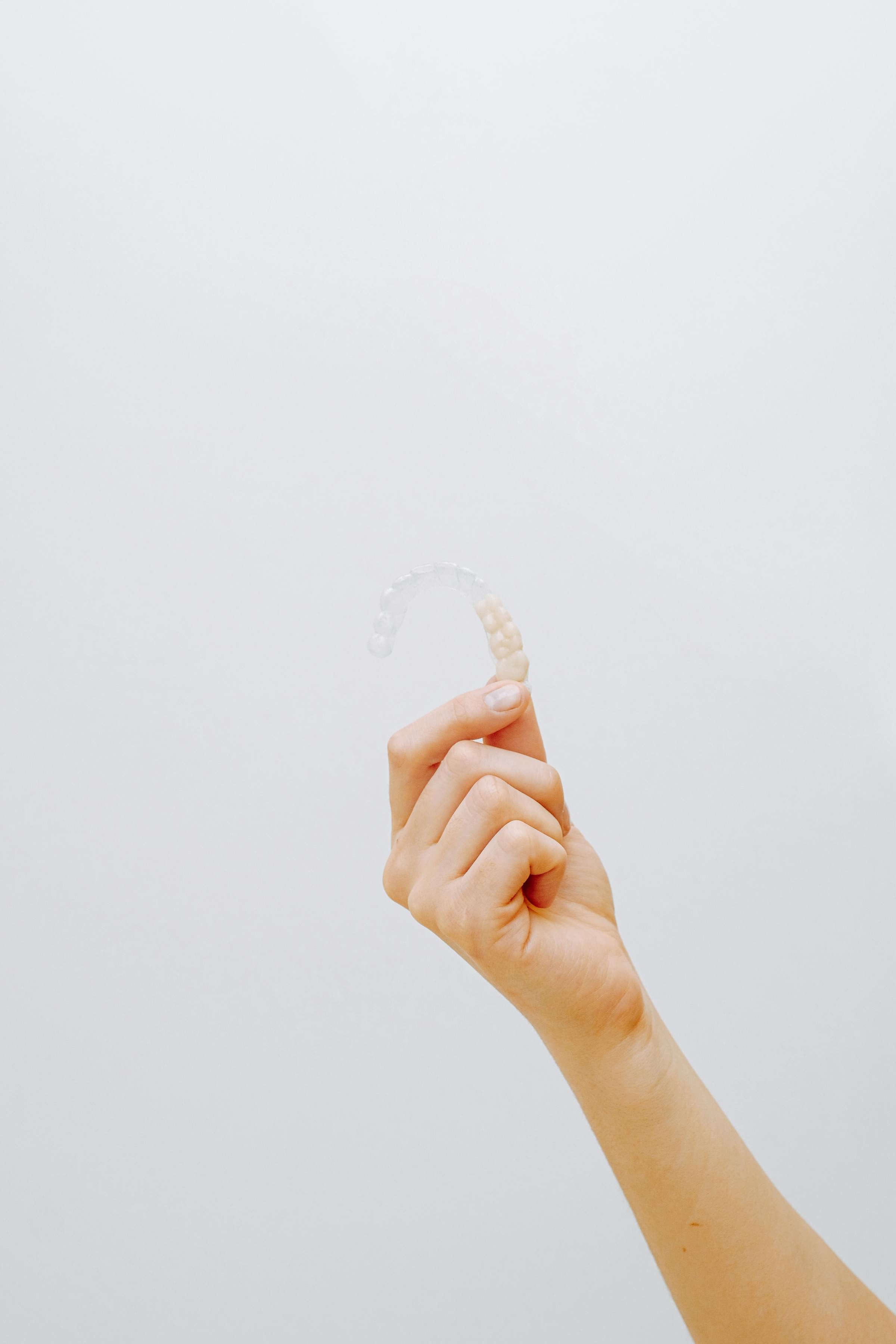 A clear plastic Invisalign aligner held in hand — the near-invisible alternative to fixed braces for adult orthodontic treatment