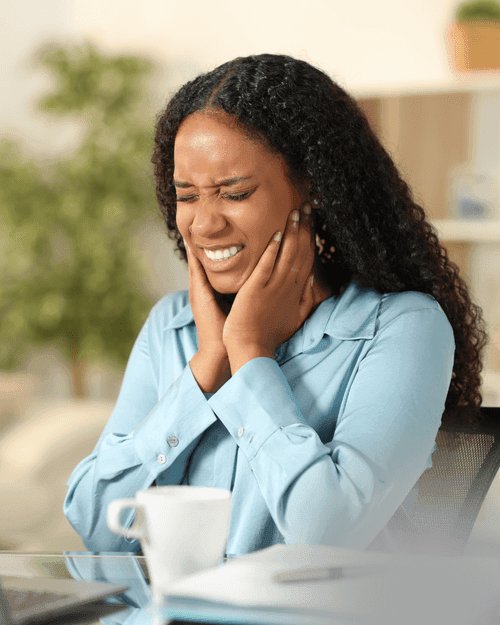 Woman holding her jaw in discomfort from TMJ pain